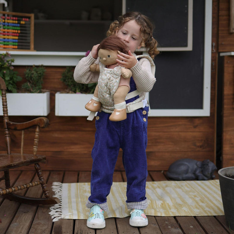 A beige floral-patterned Olli Ella Doll Carrier with padded straps designed for carrying dolls.